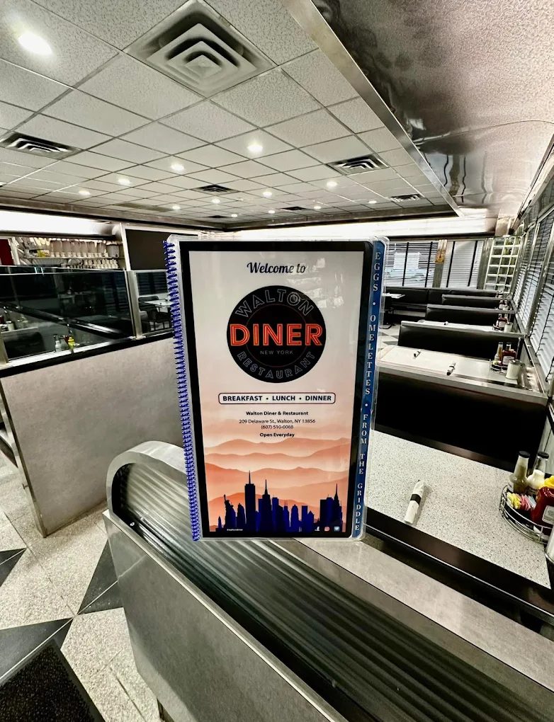 Inside Walton Diner: booths along the windows, a counter with chrome trim, and the menu on display